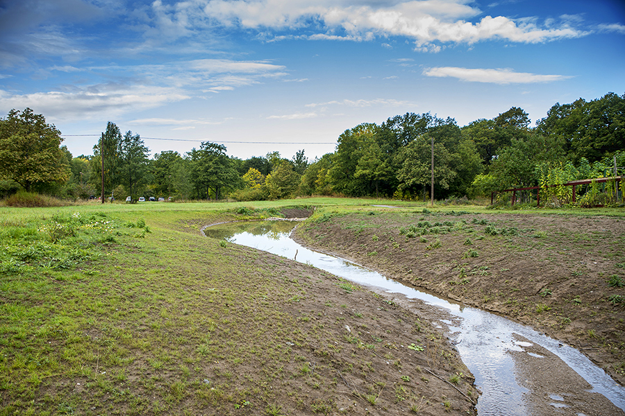 Blå himmel med en bäckfåra till höger.
